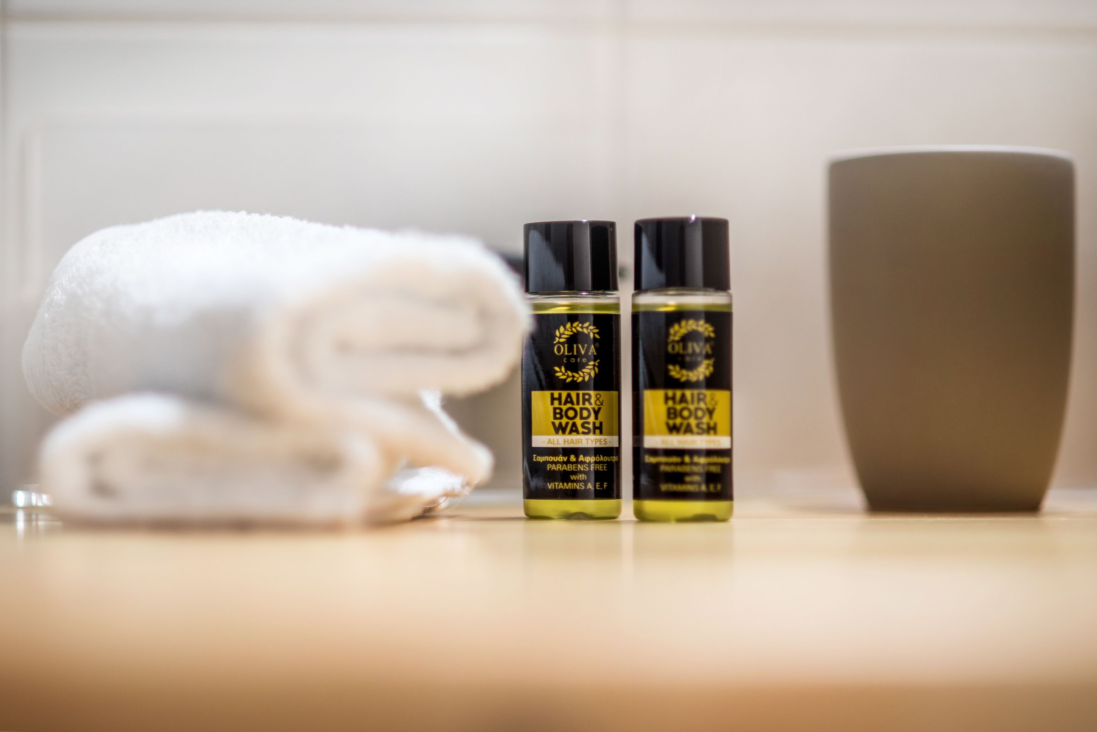 Two bottles of hair and body wash and a white towel on a countertop.