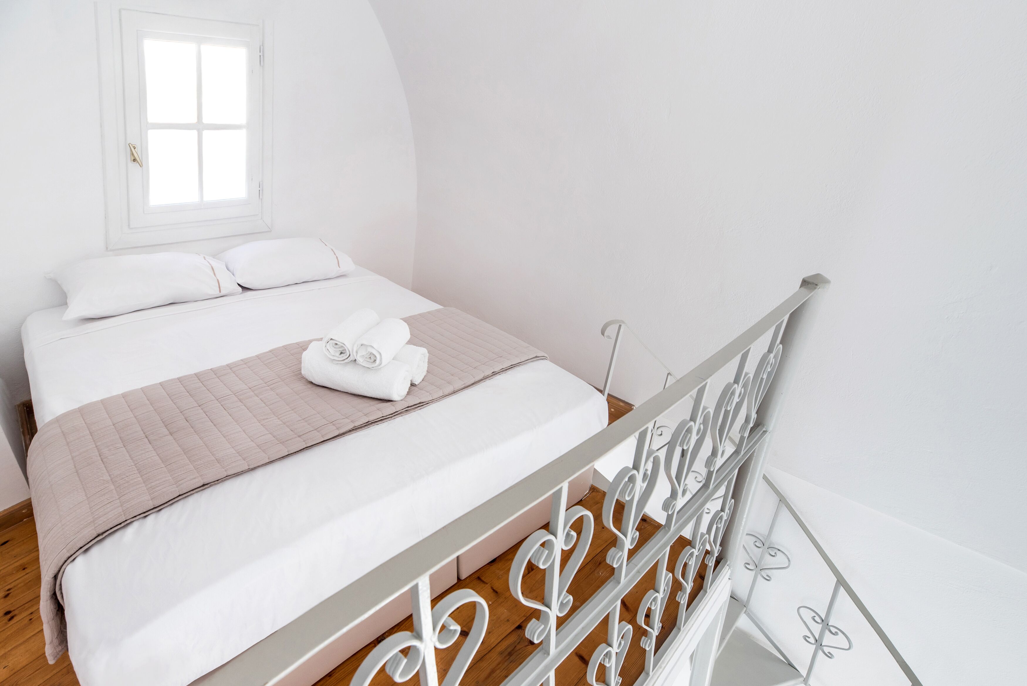 Un dormitorio con cama, almohadas, una manta y ventana.