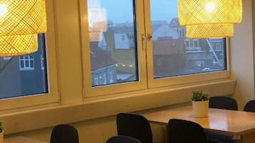 Ein Zimmer mit zwei großen Fenstern, einem Holztisch und schwarzen Stühlen.