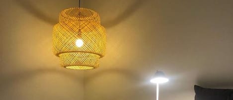 A hotel room with a bed, two chairs, a small table, and a hanging light fixture.