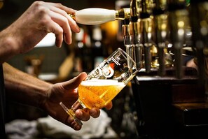 Une main tenant un verre dans lequel on verse de la bière à partir d’une tireuse.