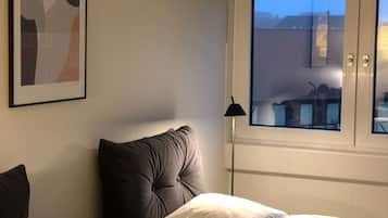 A hotel room with a bed, a window with a view, and a framed abstract artwork on the wall.