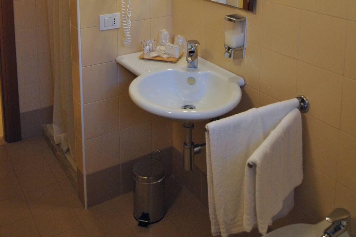 A bathroom with a sink, mirror, hairdryer, and towel rack.