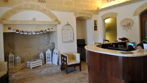A reception area with a stone wall, a wooden reception desk, a chair, and a birdcage.