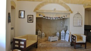 A cozy living room with two wooden chairs, a fireplace, and a stone wall.