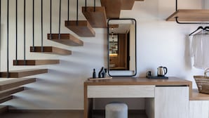 A modern interior with a wooden staircase, a desk with a mirror, and a hanging garment rack. - Poseidon Villas (Skiathos)