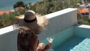 A person sitting by a pool with a view of a body of water and a distant coastline. - Poseidon Villas (Skiathos)