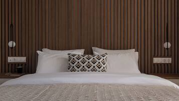 A neatly made bed with white linens and a patterned pillow, set against a wooden slatted wall.