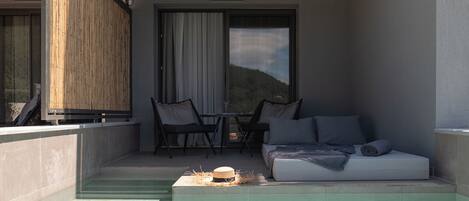 Un balcón moderno con piscina, sofá y zona de comedor con sillas y mesa.
