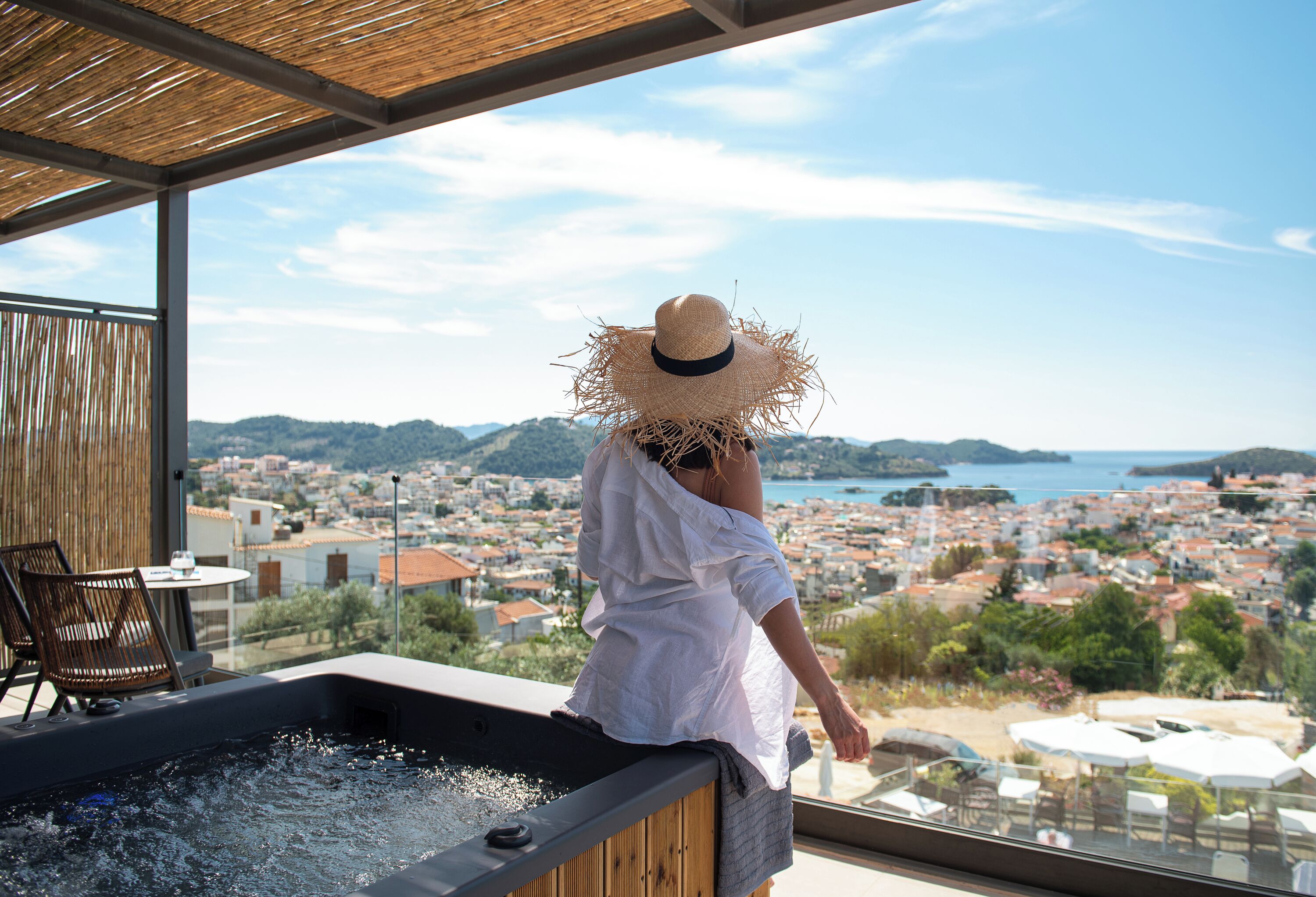 Une personne se détend dans un bain à remous avec vue sur une ville côtière.