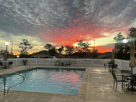 Una piscina al aire libre, sombrillas, sillones reclinables de piscina