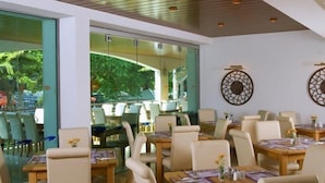 A restaurant with indoor seating, glass walls, and decorative wall art. - Hotel Flamingo (Albena)