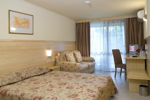 Habitación de hotel con dos camas, un escritorio, una silla, un televisor y una ventana con cortinas.