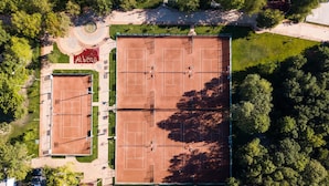 An aerial view of a tennis court complex with multiple courts, surrounded by trees and a parking area. - Hotel Flamingo (Albena)