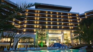 A hotel with multiple balconies, a swimming pool, and a covered area with lounge chairs. - Hotel Flamingo (Albena)