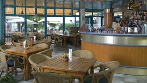 An outdoor dining area with wicker furniture, a bar with bottles, and a decorative airplane. - Hotel Kaliopa (Albena)