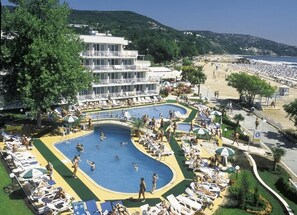 A resort with a large pool area, multiple levels of a building, and a beach in the background. - Hotel Kaliopa (Albena)