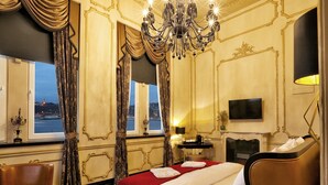A luxurious hotel room with a large bed, a chandelier, a view of the city through the window, and a television on the wall. - Nordstern Hotel Galata (Istanbul)