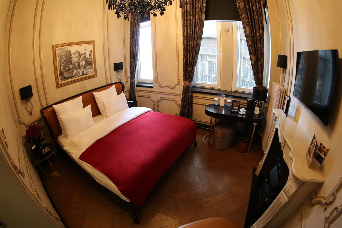 Una habitación de hotel con una cama grande, una mesita con lámpara, un televisor y una chimenea.