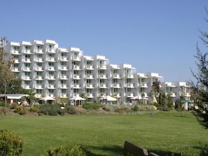 A multi-story hotel with balconies, a lawn in the foreground, and a clear sky. - Hotel Laguna Beach (Albena)