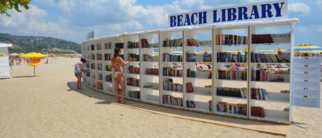 A beach library with bookshelves and a sign reading "BEACH LIBRARY".