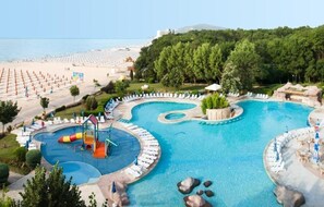 A resort with a large swimming pool, a beach, and a forested area. - Hotel Laguna Beach (Albena)