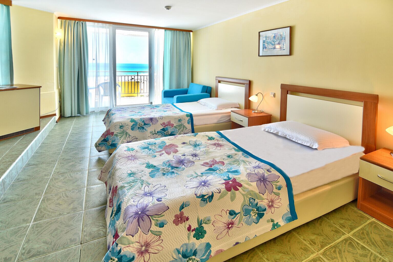 A hotel room with two beds, a balcony, and a view of the sea.