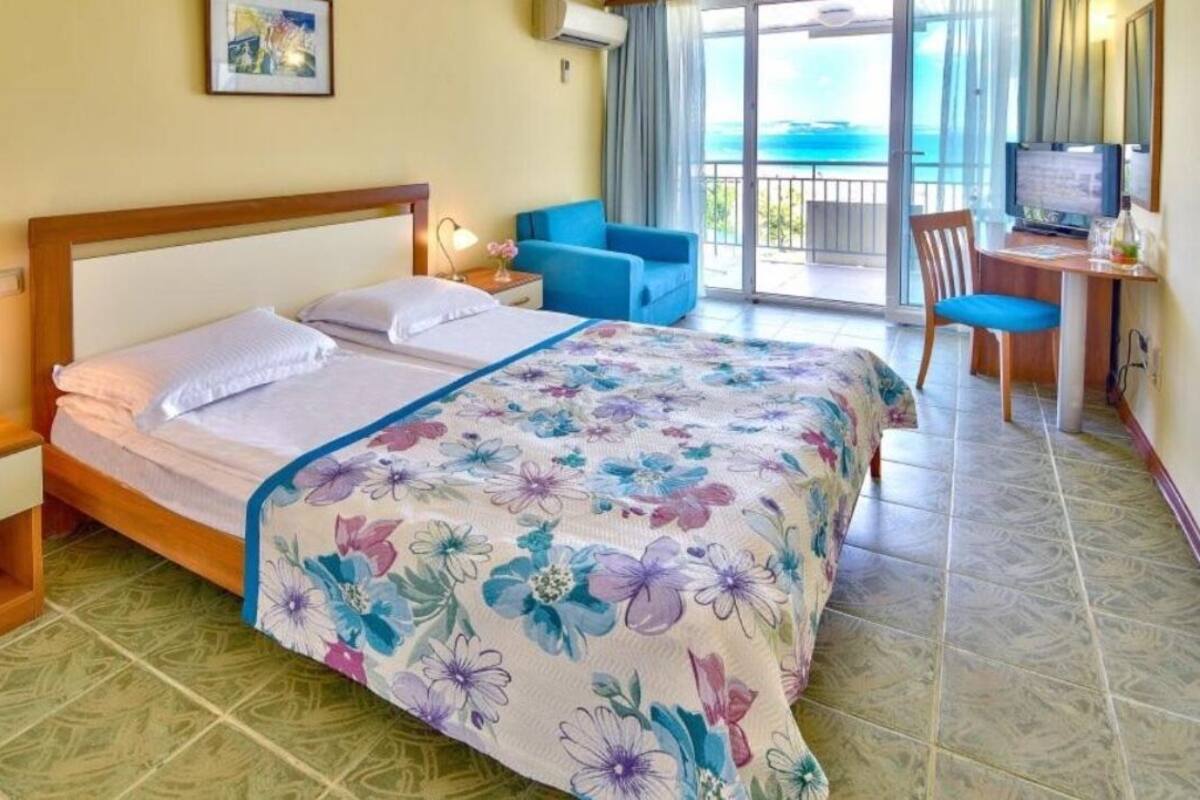 Habitación de hotel con cama, escritorio, silla y vista al océano.