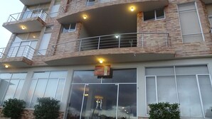 Um hotel com vários andares, fachada de tijolos, varandas e grandes portas de vidro.