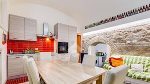 A modern kitchen with a dining area, a stone wall, and a sofa. - Casa Particular Underground (Rome)