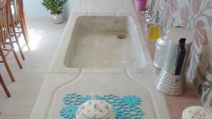 A kitchen with a sink, a decorative blue mat, a teapot, and a small plant. - Casa Particular Underground (Rome)