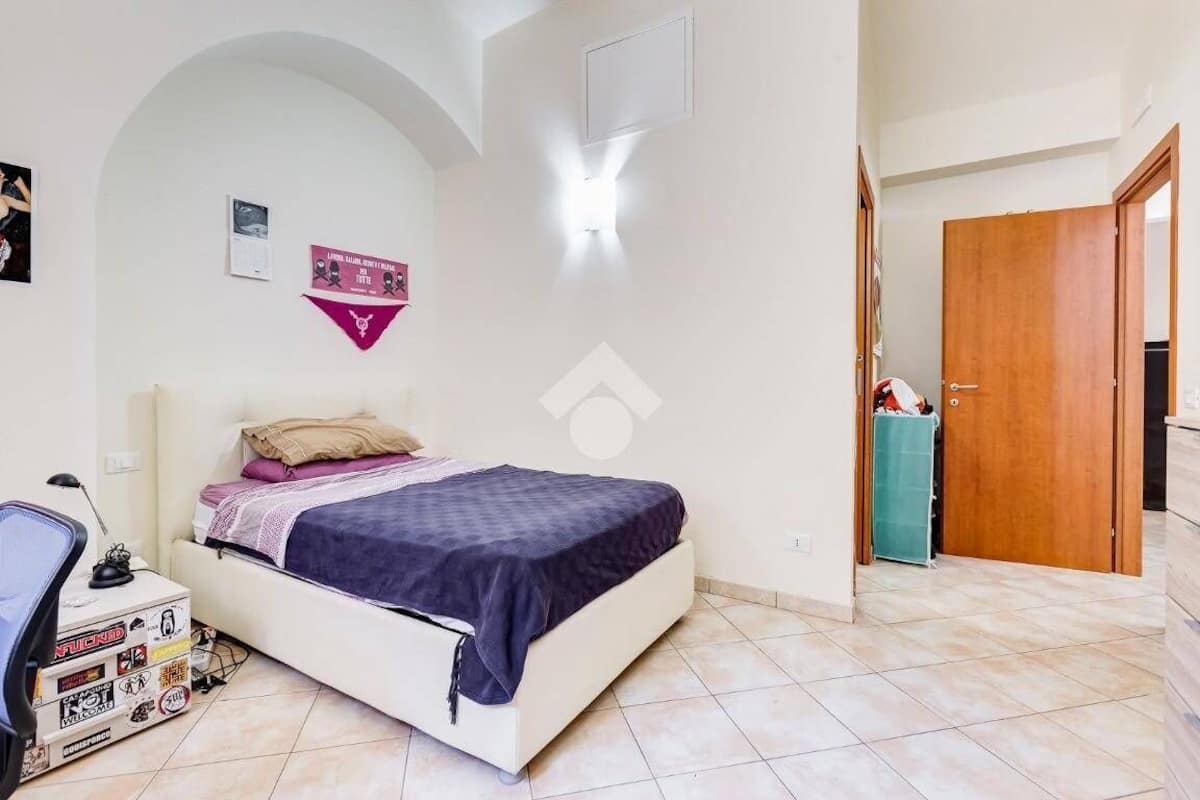 A bedroom with a bed, a desk, and a wardrobe.