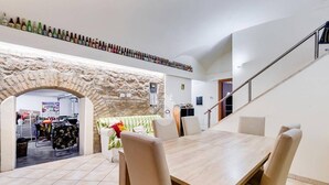 A dining area with a stone archway, a staircase, and a wine rack above the table. - Casa Particular Underground (Rome)
