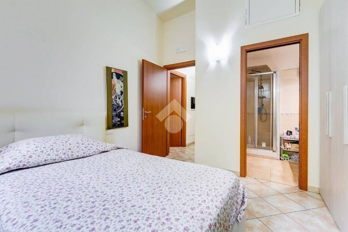 A bedroom with a bed, a door leading to a bathroom, and a hallway.