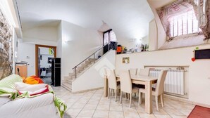 A modern living room with a dining area, a staircase, and a kitchen in the background. - Casa Particular Underground (Rome)