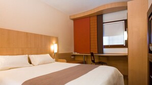 Una habitación de hotel con una cama grande, un escritorio y una silla.