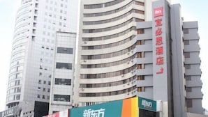 Un edificio de varios pisos con fachada curva, que muestra señalización para un hotel y un centro de negocios.