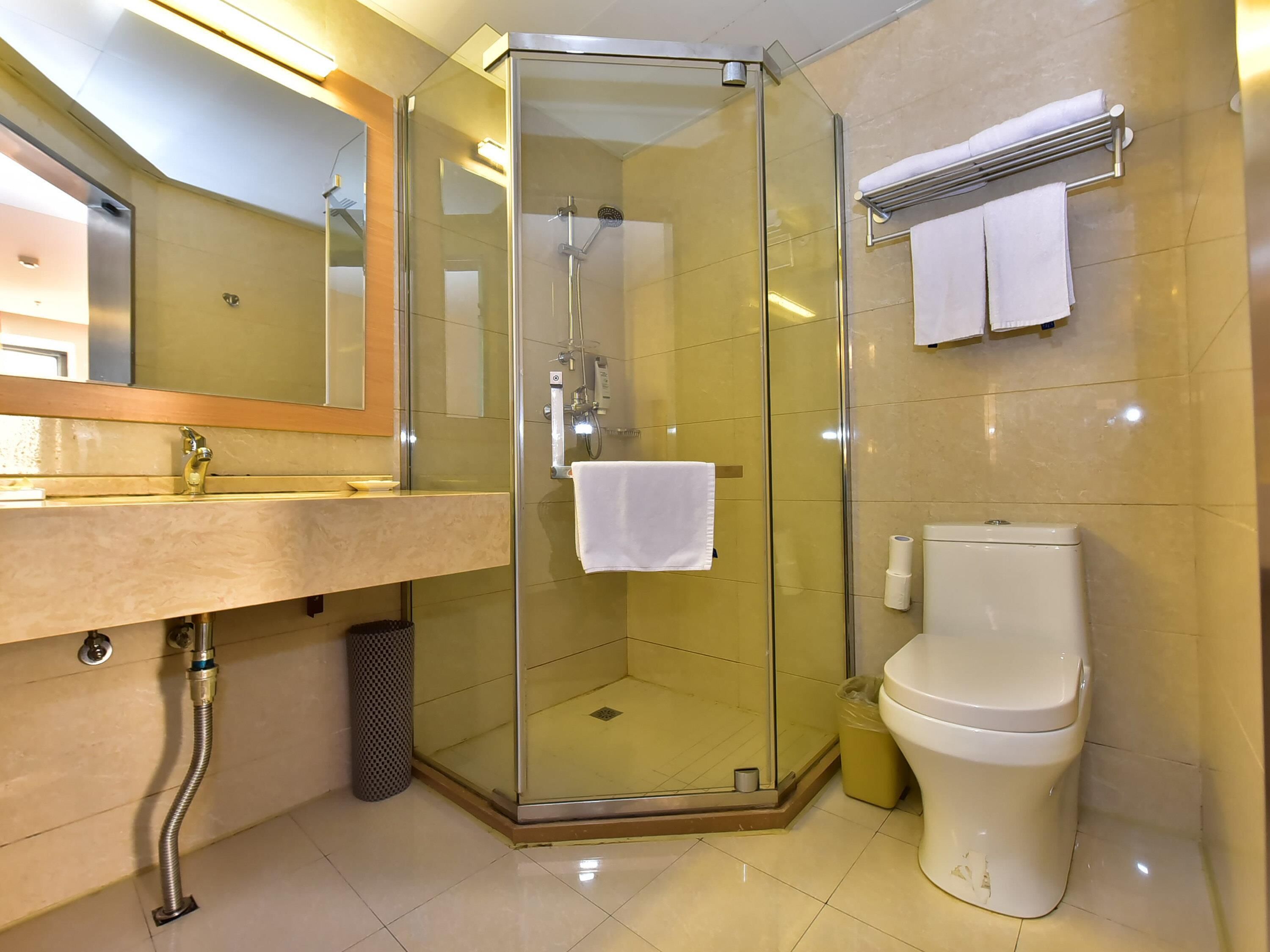 A modern bathroom with a glass-enclosed shower, a sink with a mirror, and a toilet.