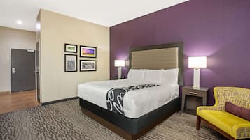 A hotel room with a bed, bedside tables, a chair, and wall art.