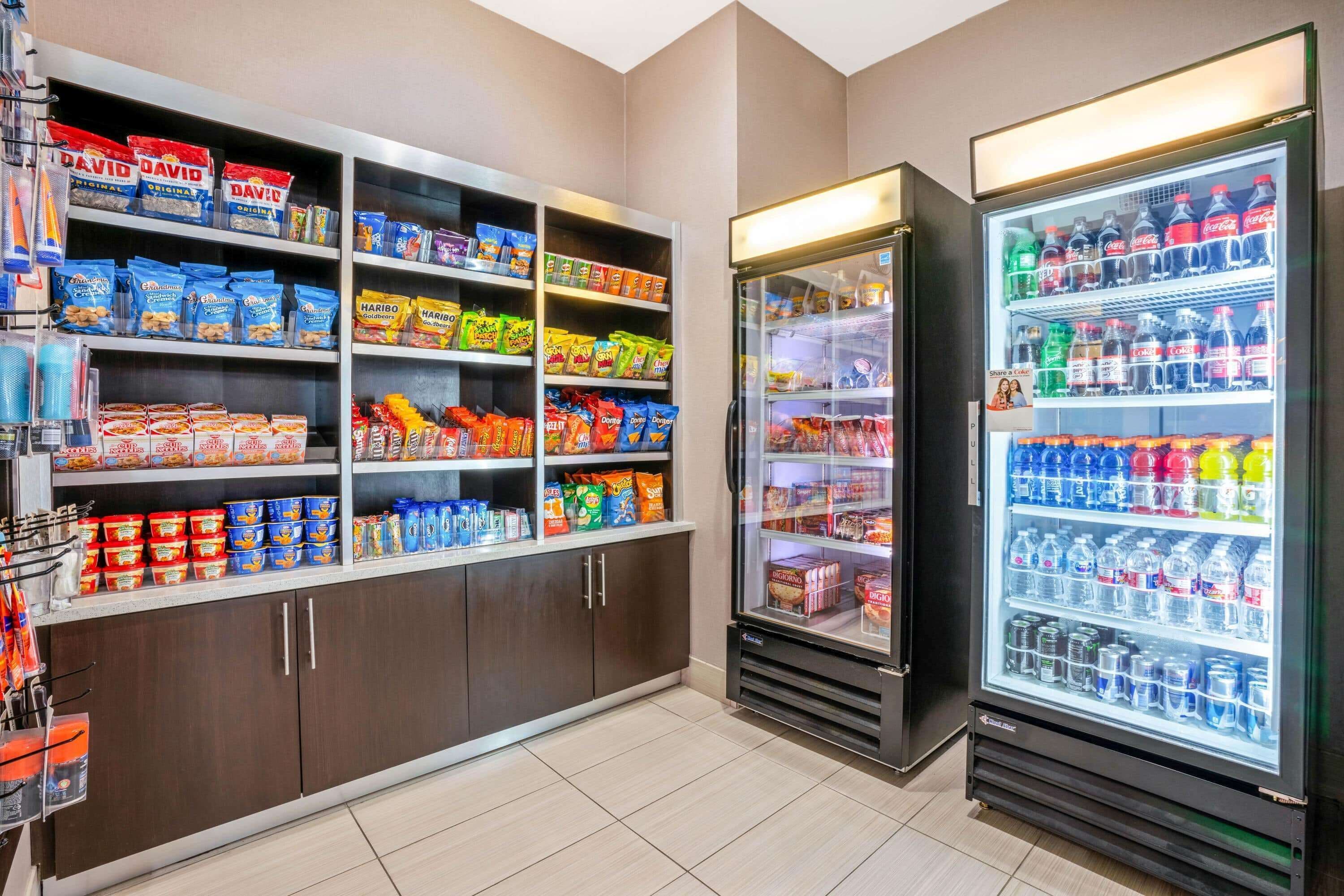 A self-service snack and beverage station with various packaged snacks, beverages, and canned goods.