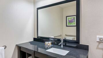 A modern bathroom with a black countertop, white sink, and a large mirror.