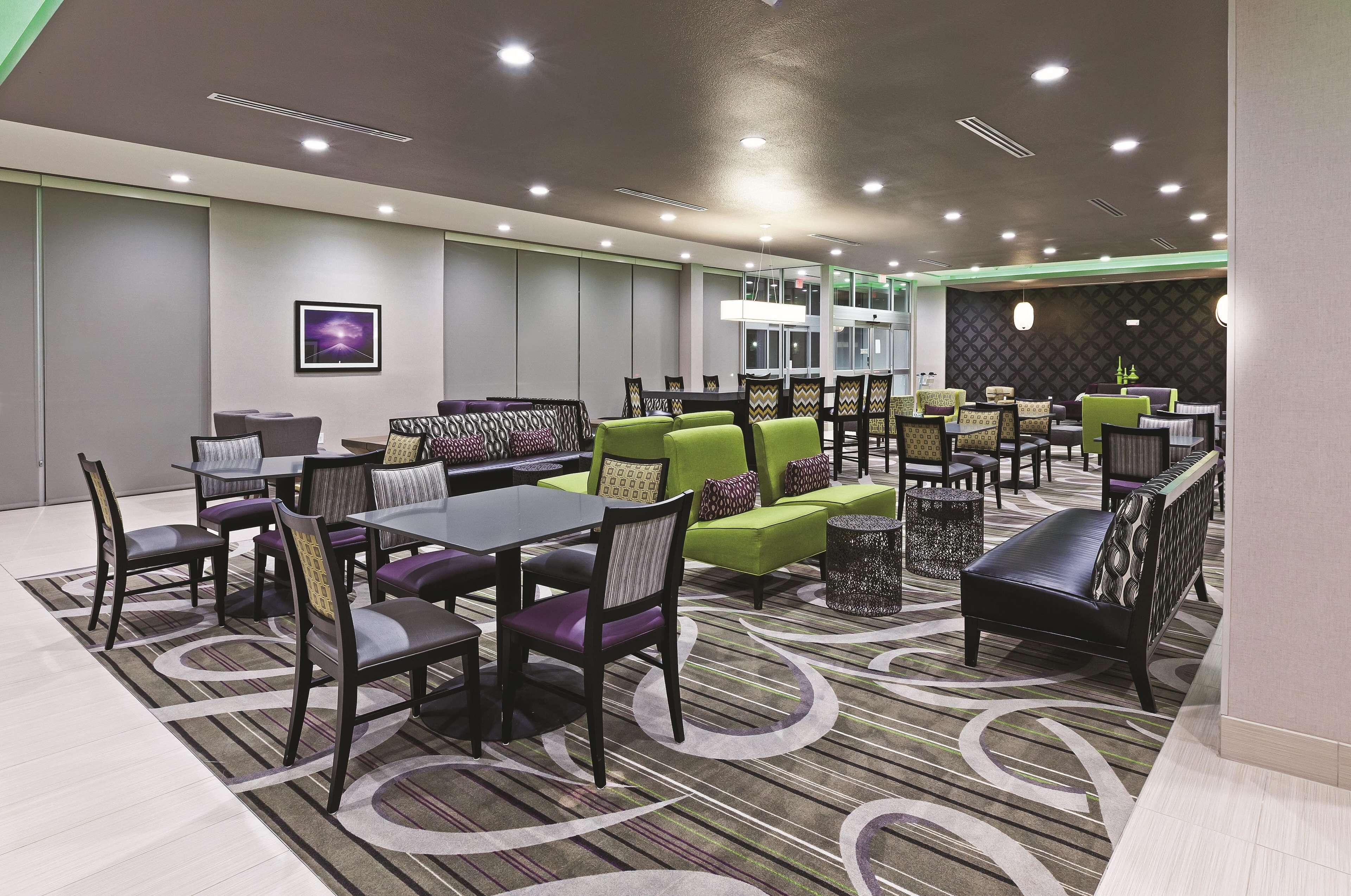 A modern hotel lobby with a mix of seating options including tables, chairs, and sofas.