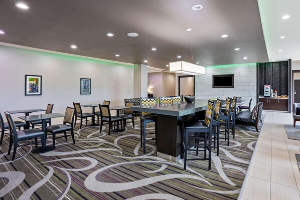 Un comedor de hotel con una mesa larga común, varias sillas y una alfombra estampada.