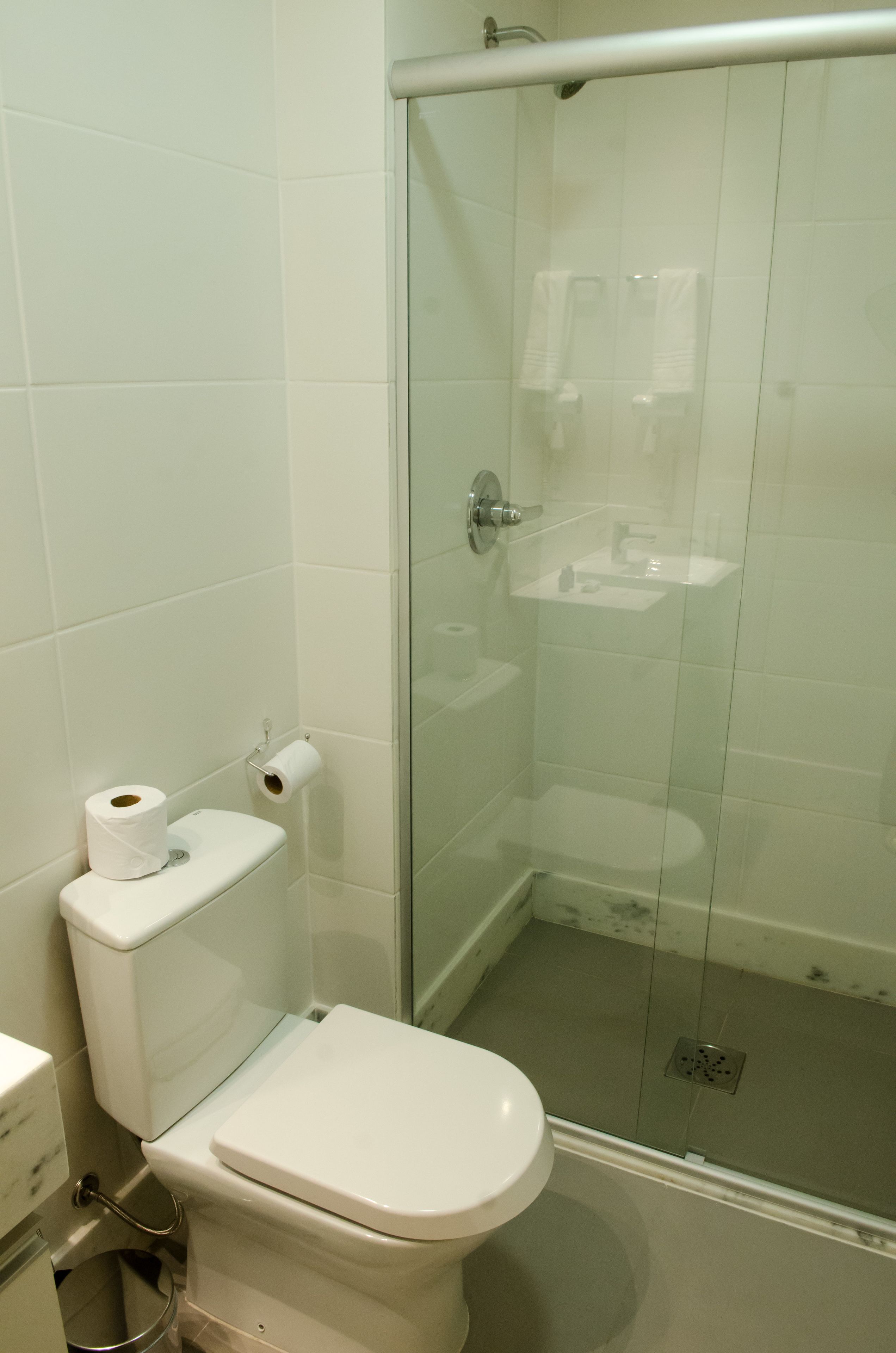 Un baño con inodoro, cabina de ducha de vidrio y lavabo.