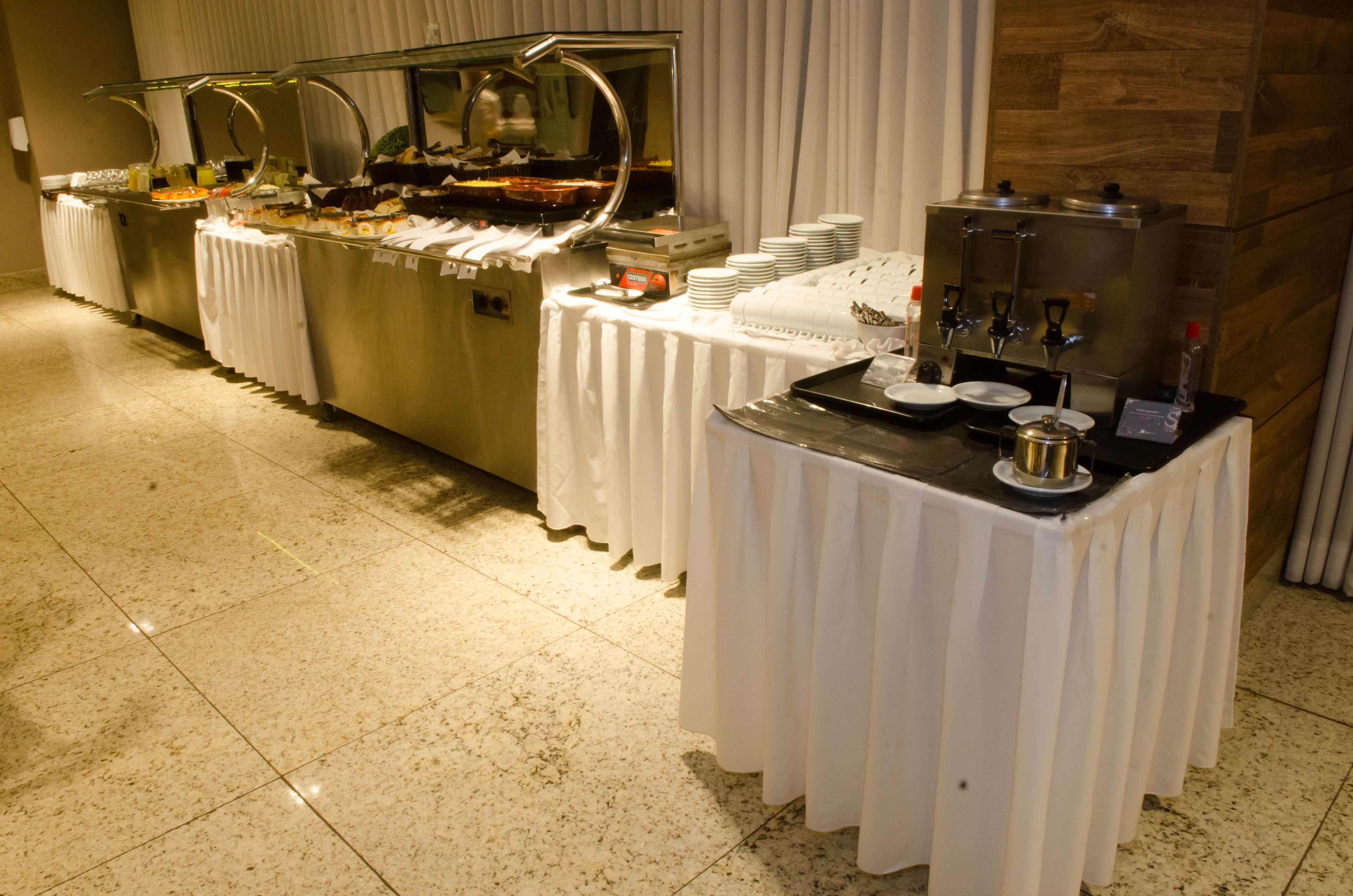 A buffet setup with multiple serving stations, including hot and cold food options, and a coffee station.
