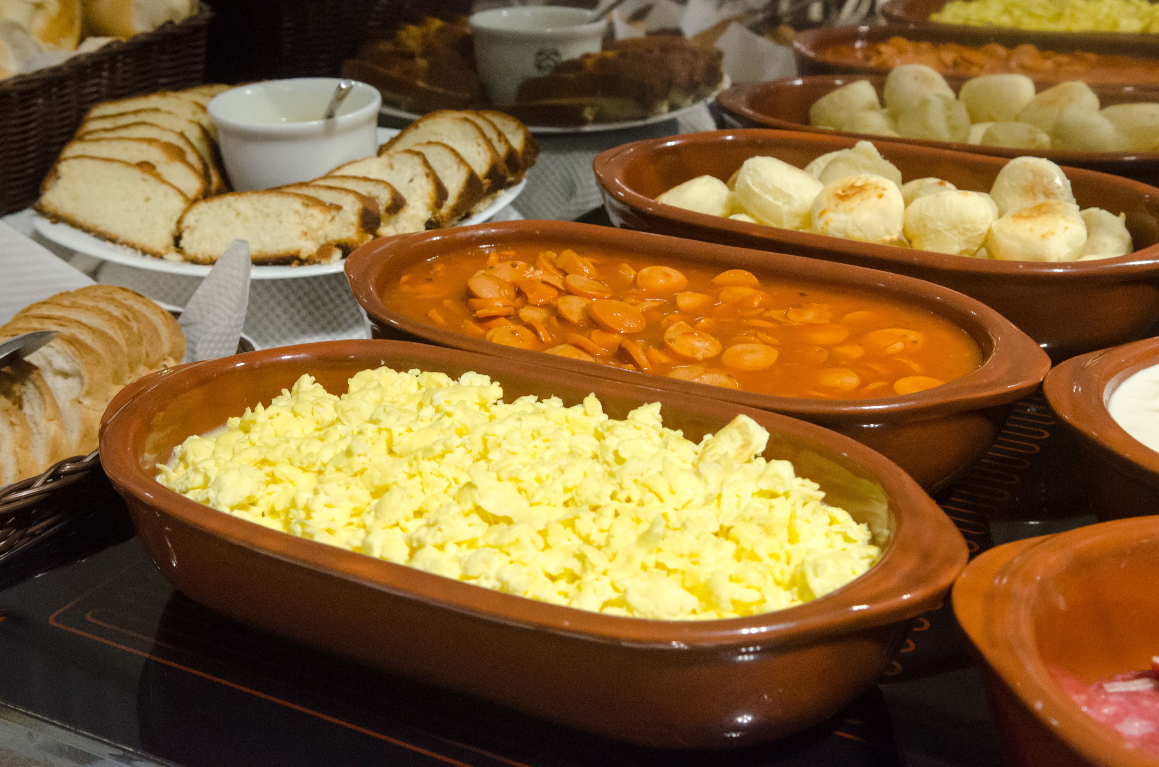 A buffet with various dishes including bread, beans, and scrambled eggs.