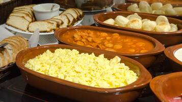 A buffet with various dishes including bread, beans, and scrambled eggs.