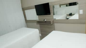 A hotel room with a bed, a bedside table, a TV mounted on the wall, and a mirror.
