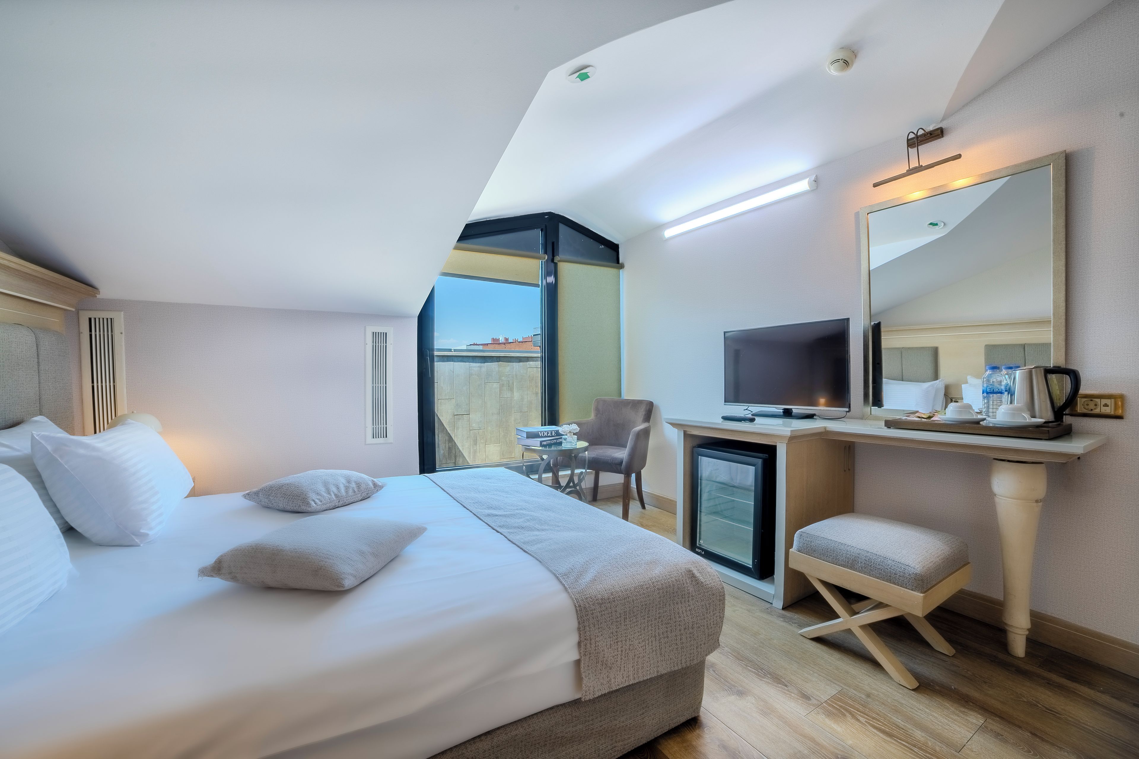 Une chambre d’hôtel comprenant un lit, un bureau avec un ordinateur, une chaise et un téléviseur.