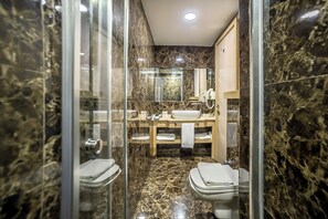 Un bany modern amb una dutxa envidriada, un moble de bany de fusta i dues vàteres.